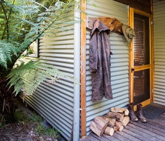 logs for fire stacked outside with rustic boots and coat