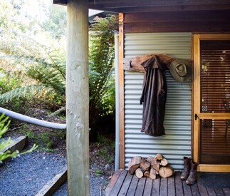 entry with logs for fire stacked with boots and coat