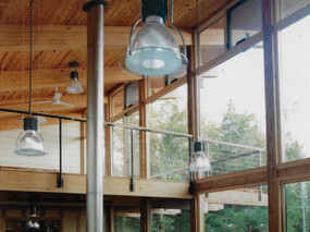 Modern heavy timber post and beam house. Interior view showing south facing window wall with loft level and deck.