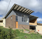 Front yard extension featuring brick, corrugated metal siding, timber screen wall, UPVC windows and bluestone landscaping.