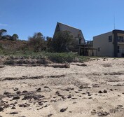 The new beach house design replaces the existing triangular shack and is placed to avoid native vegetation and rock features.