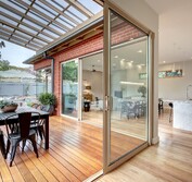 View looking onto wood decked veradah from interior. Shows interior kitchen, dining and living area with hardwaood flooring and marble benchtops.Living Room extension and veranda.