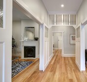 Interior view of bungalow entry with restored fretwork and new timber flooring. The fireplace in the Lounge on the left was completely rebuilt. Stringy Bark solid hardwood flooring was installed throughout.