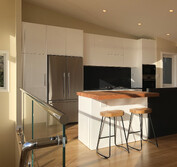 Custom kitchen design featuring two-pac painted panels, honed black and polished Blue Pearl granite, and Tassie Oak butcher block to match the flooring.