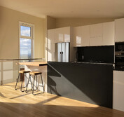 Custom kitchen design featuring two-pac painted panels, honed black and polished Blue Pearl granite, and Tassie Oak butcher block to match the flooring.