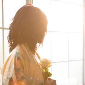 Image of a woman looking out a window holding a rose