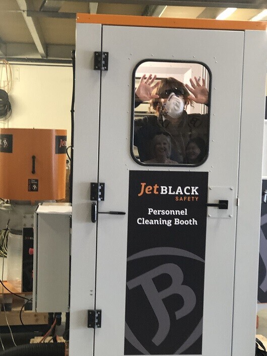 One of the Blackwoods staff members inside the booth with PPE on, face to window