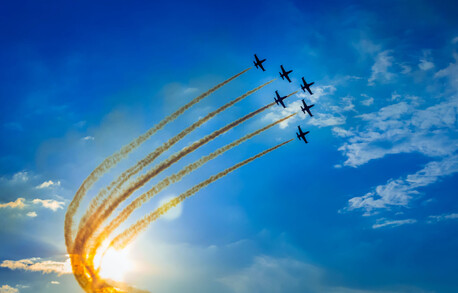 Group of aeroplanes flying together in sky with jet mist